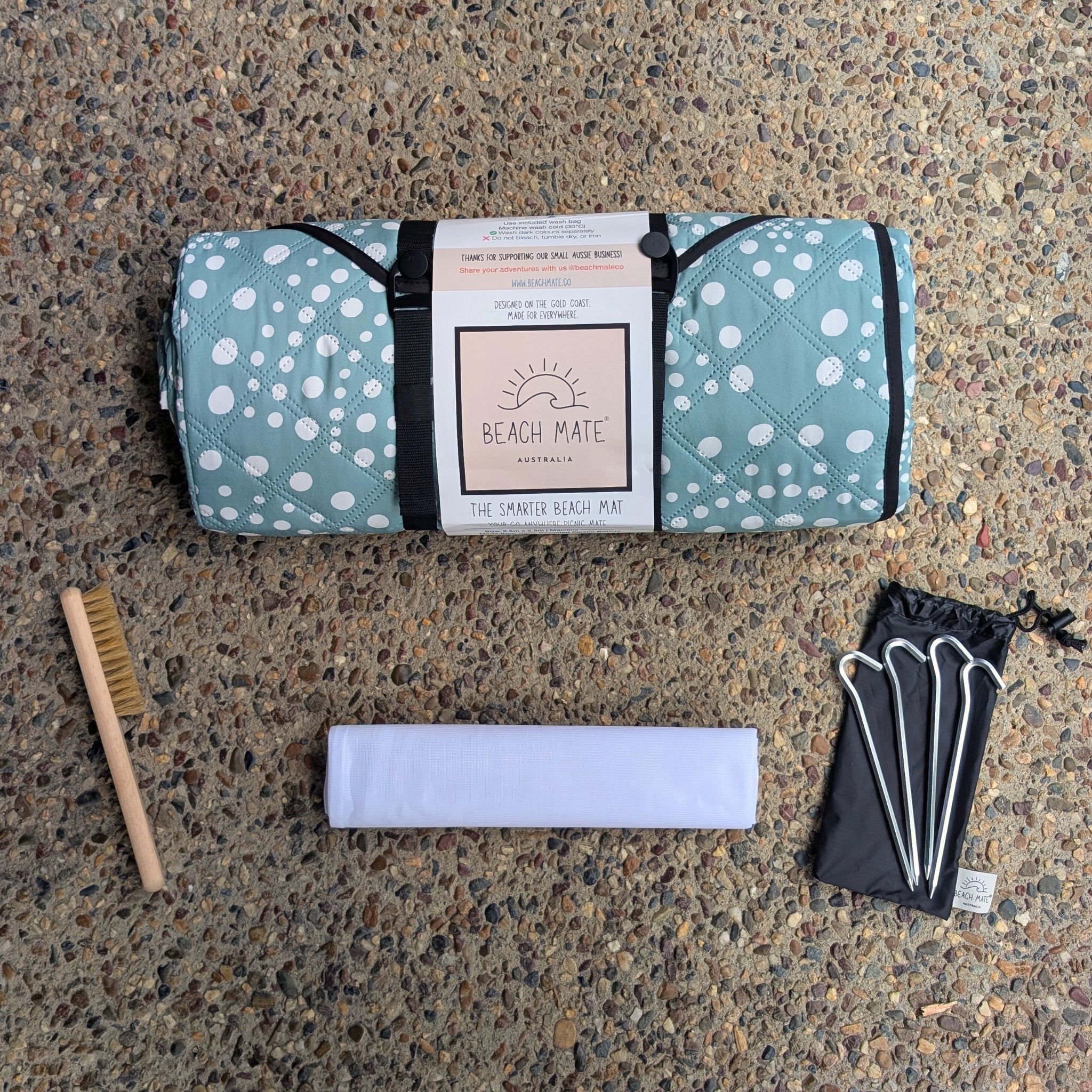 Snapper Rocks Beach Mate rolled with accessories — pegs, wash bag, and sand brush included.
