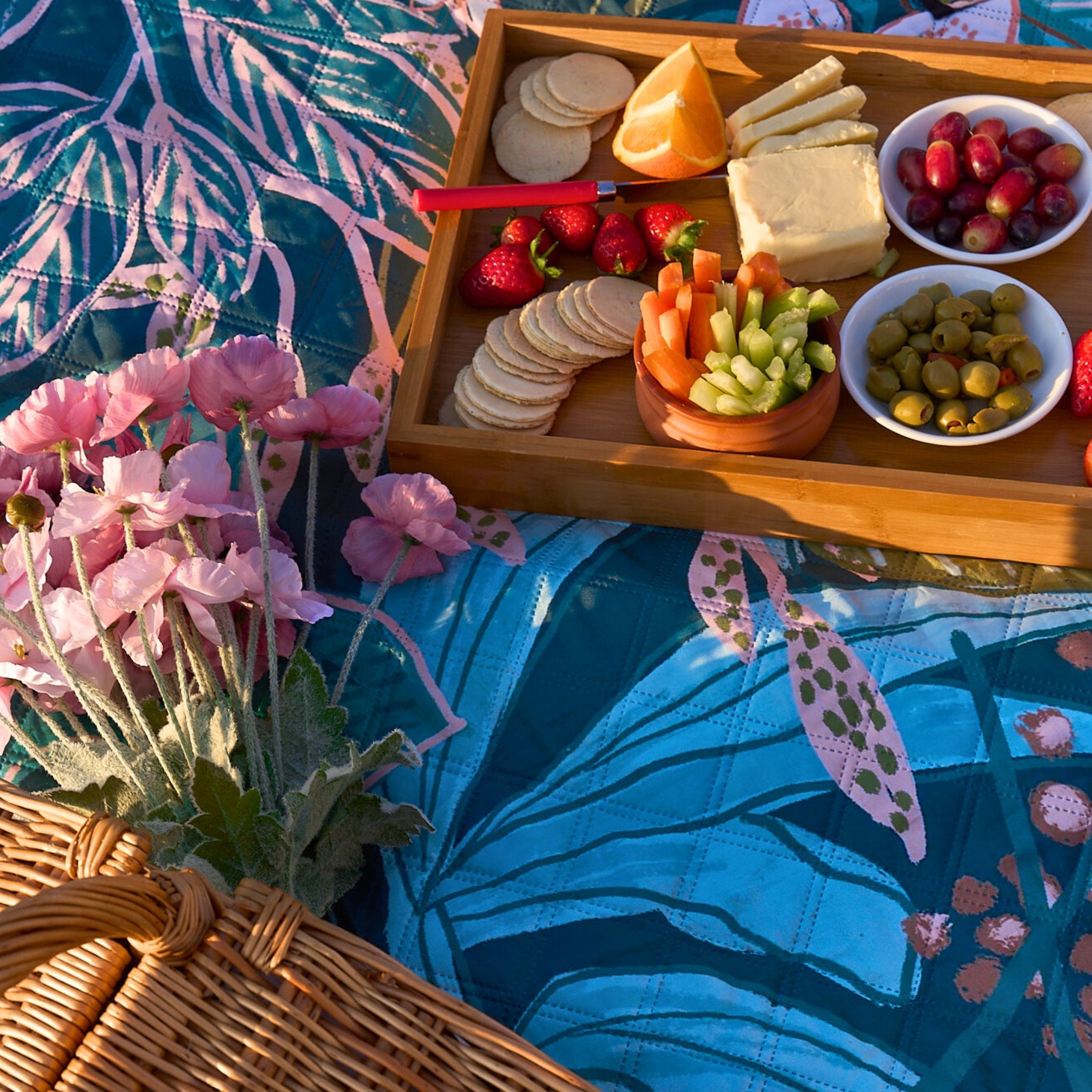 Close-up of the Talle Valley Beach Mate with picnic spread, flowers, and tropical print detail.