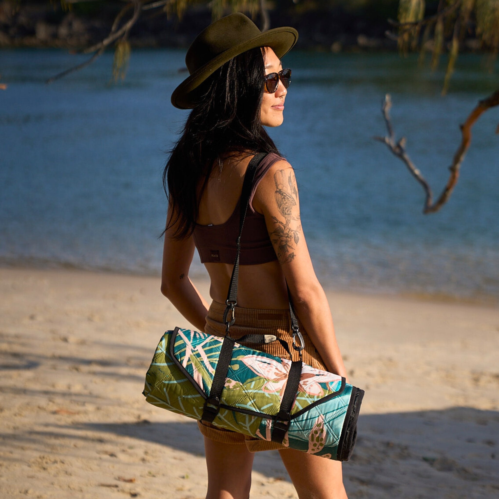 Carrying the rolled Talle Valley Beach Mate along the beach with ocean backdrop.
